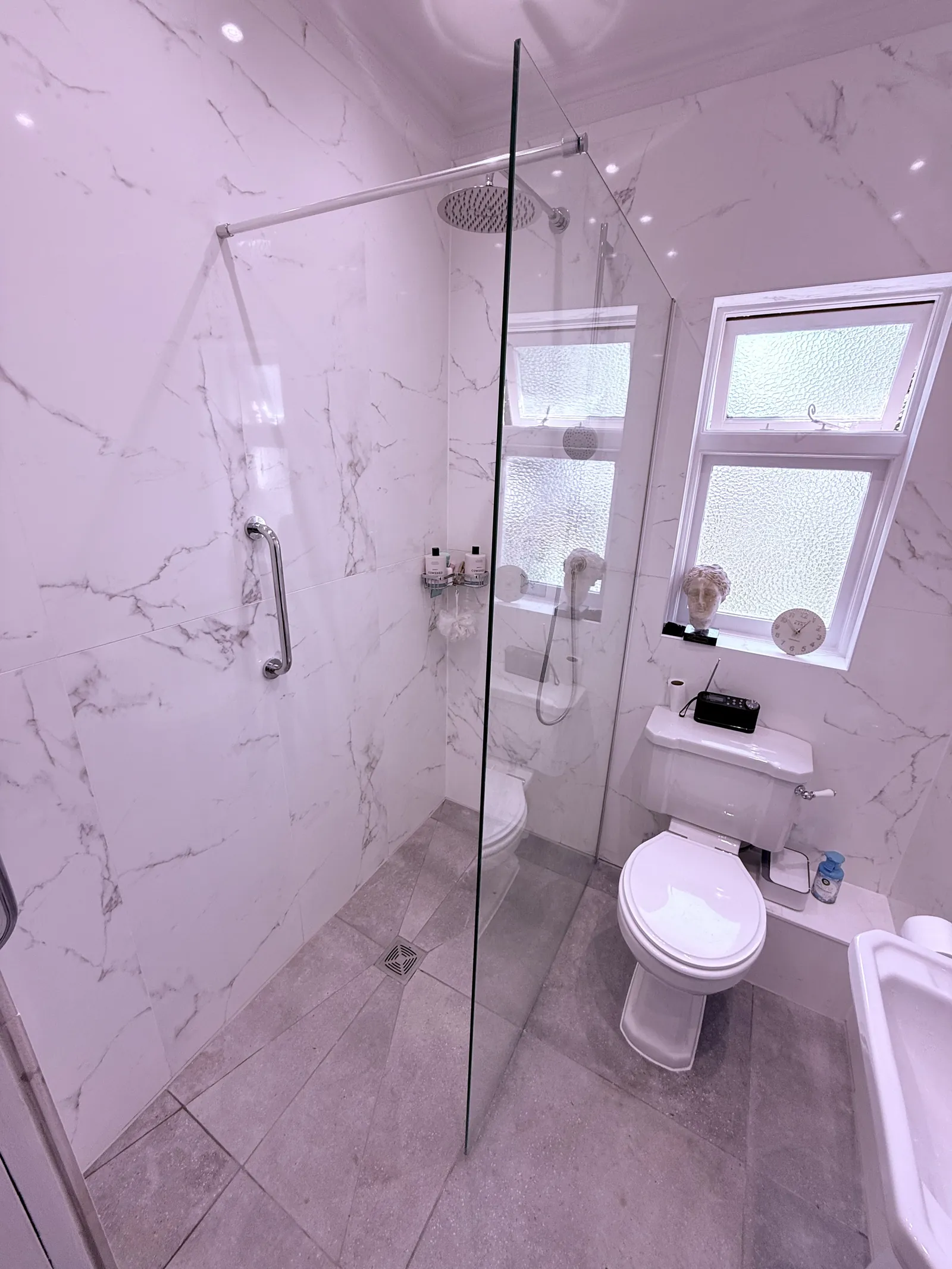 Bright walk-in shower with glass screen and marble-effect tiles