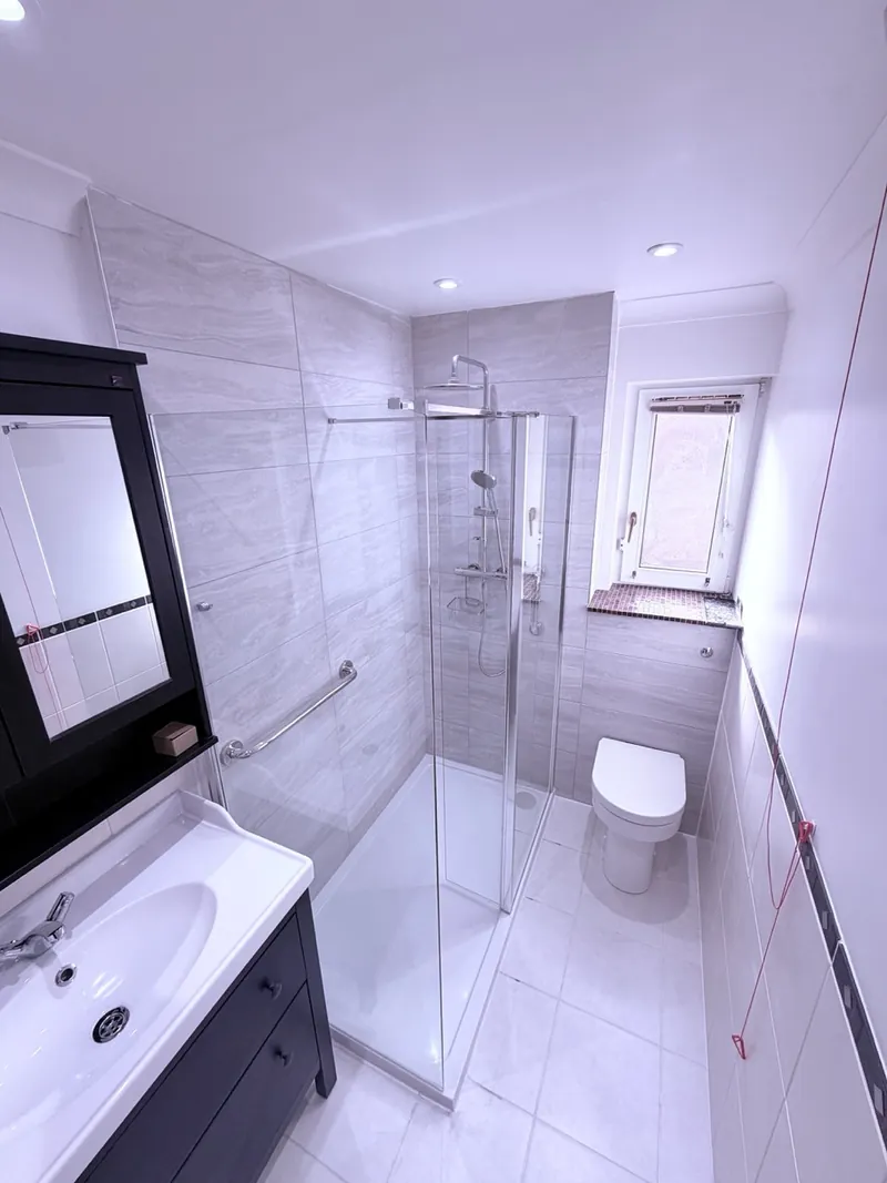 The same bathroom finished, with a walk-in shower and grab rail